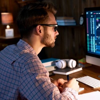 Young man sitting in front of computer screen at night. Image: Adobe